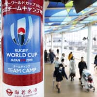 People walk past a poster promoting the upcoming Rugby World Cup in Ebina, Kanagawa Prefecture, one of the municipalities across the country that will host teams from abroad. | KYODO