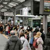 People line up to board buses in front of Kyoto Station in February 2018. Many local governments are struggling to deal with an influx of visitors amid the country\'s tourism boom. | KYODO