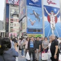 People pose for a photo in the Dotonbori district in the city of Osaka. | KYODO