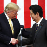 U.S. President Donald Trump shakes hands with Prime Minister Shinzo Abe aboard the Maritime Self-Defense Force\'s Kaga helicopter carrier in Yokosuka, Kanagawa Prefecture, on May 28. | REUTERS