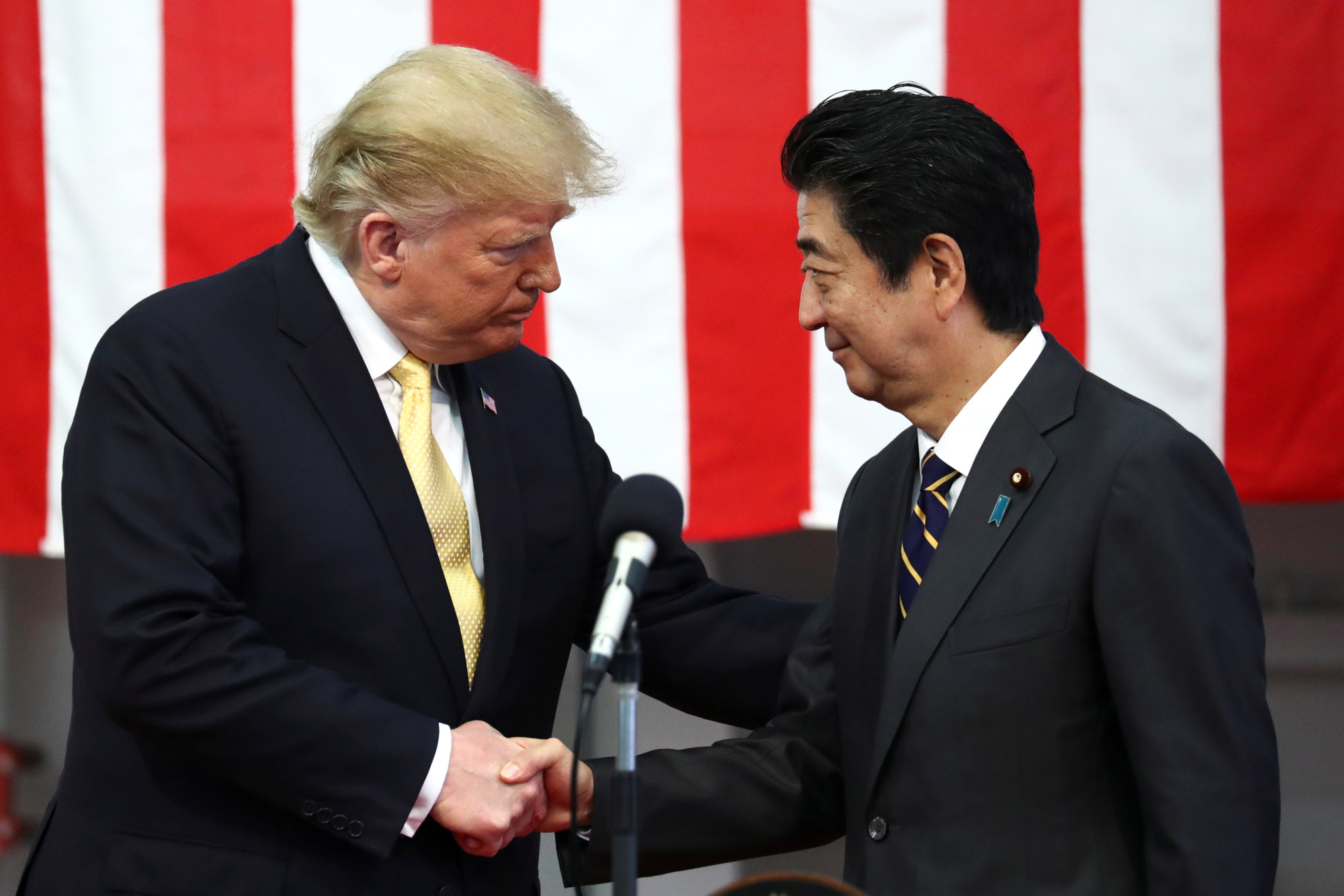 U.S. President Donald Trump shakes hands with Prime Minister Shinzo Abe aboard the Maritime Self-Defense Force's Kaga helicopter carrier in Yokosuka, Kanagawa Prefecture, on May 28. | REUTERS