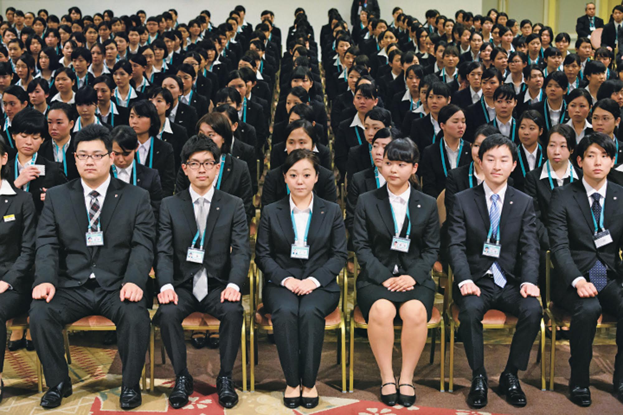 New employees of Seven & I Holdings Co. attend an initiation ceremony in Tokyo in March 2015. Last week, Prime Minister Shinzo Abe's Council on Economic and Fiscal Policy recommended that the government draw up detailed measures to bring the nationwide average minimum wage up to ¥1,000 per hour as soon as possible. | BLOOMBERG