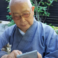 A couple of pals: The head priest of Kairyuji temple on Shiraishi Island checks an electronic dictionary while his new furry friend, a stray kitten, watches from his arms. | AMY CHAVEZ