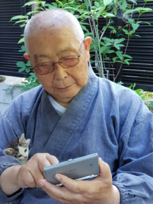 A couple of pals: The head priest of Kairyuji temple on Shiraishi Island checks an electronic dictionary while his new furry friend, a stray kitten, watches from his arms. | AMY CHAVEZ
