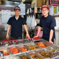 Passing down culinary traditions: Kim Ryun Gyu (right) and Nguyen Van Tien dish out varieties of kimchi at Gyeongyu Shoten, which has been in Kim\'s family for three generations. | TSUYOSHI TAGAWA