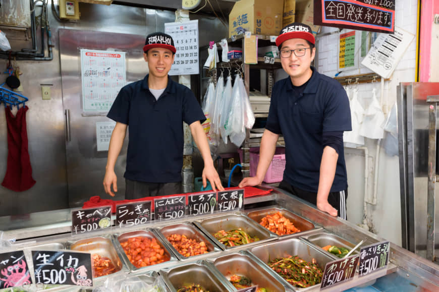 Passing down culinary traditions: Kim Ryun Gyu (right) and Nguyen Van Tien dish out varieties of kimchi at Gyeongyu Shoten, which has been in Kim's family for three generations. | TSUYOSHI TAGAWA