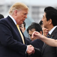 Prime Minister Shinzo Abe shakes hands with U.S. President Donald Trump aboard the Maritime Self-Defense Force helicopter carrier Kaga on May 28 in Yokosuka, Kanagawa Prefecture. | AP