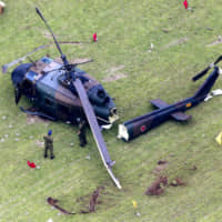 The wreckage of a Ground Self-Defense Force UH-1J helicopter lies on the ground Friday after a botched landing exercise at Camp Tachikawa, in the western suburbs of Tokyo, earlier in the day. The two crew members aboard were not injured. | KYODO