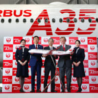 Japan Airlines President Yuji Akasaka (center) and others pose in front of an Airbus A350-900 passenger jet on Thursday at Haneda airport in Tokyo. Last week JAL received its first delivery of the 369-seat aircraft, which will be used for services connecting Tokyo and Fukuoka from Sept. 1. JAL plans to deploy 31 A350 jets by the mid-2020s. | KYODO