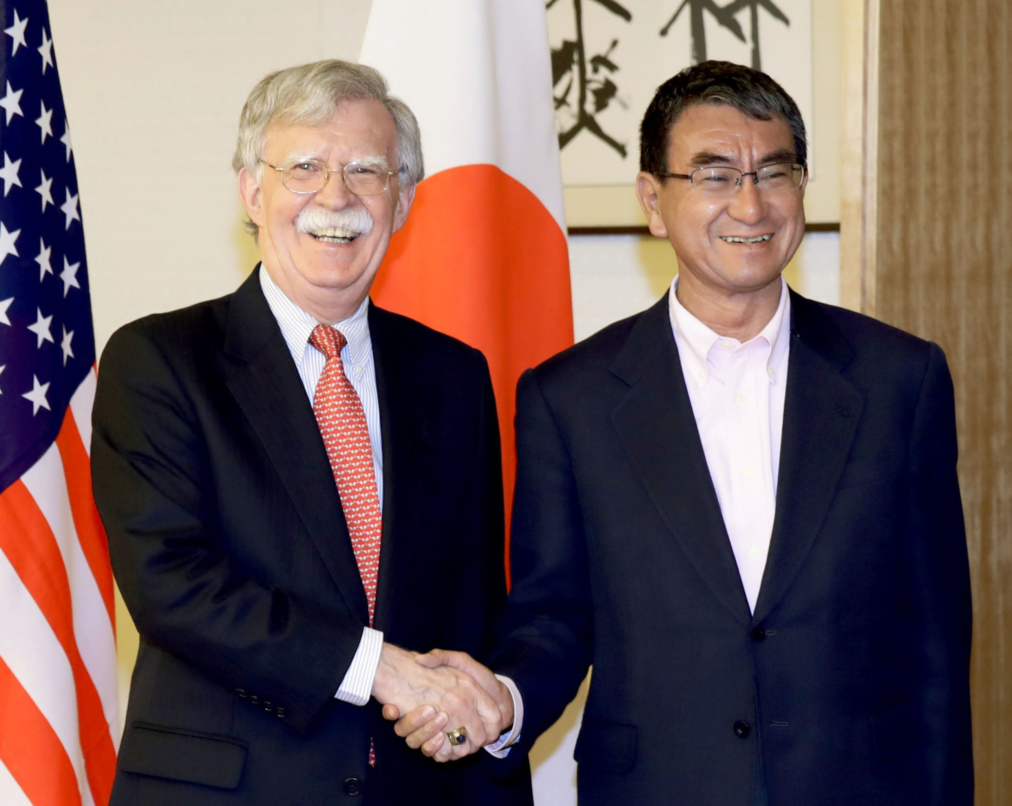 U.S. National Security Adviser John Bolton and Japanese Foreign Minister Taro Kono shake hands at the Foreign Ministry in Tokyo on Monday. | KYODO