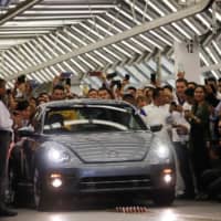 Employees take pictures of a Volkswagen Beetle during a ceremony marking the end of production of VW Beetle cars, at the company\'s assembly plant in Puebla, Mexico, Wednesday. | REUTERS