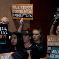 An attendee holds up a \"Wall Street Is Driving Retail Bankruptcies\" sign during a news conference on the Stop Wall Street Looting Act on Capitol Hill in Washington July 18. Sen. Elizabeth Warren\'s plan would make private-equity firms responsible for debts and retirement pension obligations of companies they purchase, while making their profits contingent on the success of the entities they control. | BLOOMBERG