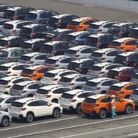Cars await shipment at a port in Kawasaki. The government has cut its economic growth forecast for fiscal 2019, citing weak exports caused mainly by a slowdown in demand from China. | KYODO