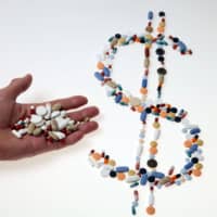 Pharmaceutical tablets and capsules are arranged in the shape of a dollar sign on a table in this picture illustration taken in 2014. | REUTERS