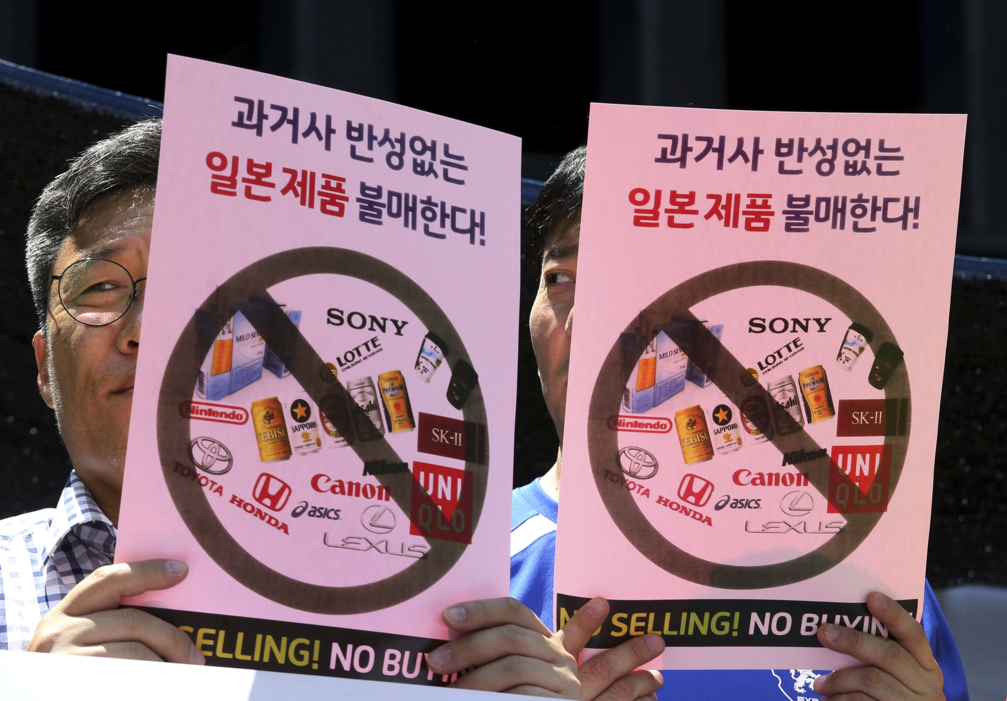 South Korean merchants attend a rally in front of the Japanese Embassy in Seoul on Friday to denounce export controls announced by Tokyo. The signs read: 'Boycott Japanese products.' | AP