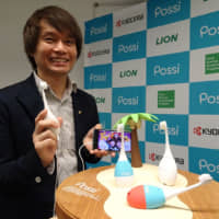 Tomohiro Inagaki, an engineer behind a music-playing toothbrush dubbed Possi, poses with the product on Wednesday in Tokyo. | KAZUAKI NAGATA