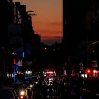 People walk along a dark street near Times Square in Manhattan during a blackout on Saturday. | REUTERS