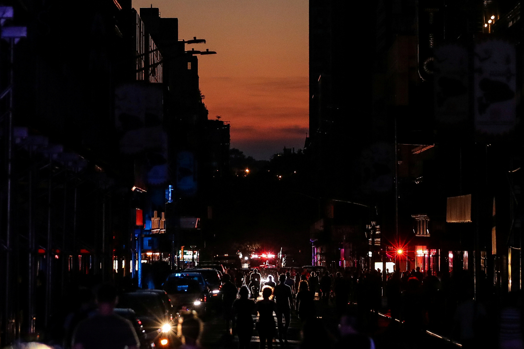 People walk along a dark street near Times Square in Manhattan during a blackout on Saturday. | REUTERS