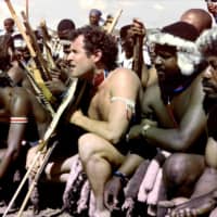 A 1989 photo taken in Keate\'s Drift, South Africa, shows Johnny Clegg (center), leader of the pop group Savuka, in a traditional Zulu outfit during his wedding with Jennifer Bartlett. | AFP-JIJI