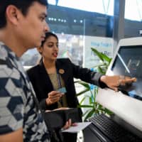 An airport staff member shows a passenger how to register his personal details at a facial recognition counter at the Rajiv Gandhi International Airport in Hyderabad on Friday. | AFP-JIJI