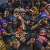 Rohingya Muslim women, who crossed over from Myanmar into Bangladesh, stretch their arms out to collect sanitary products distributed by aid agencies near the Balukhali refugee camp, Bangladesh, in 2017. International Criminal Court prosecutor Fatou Bensouda said Thursday she has filed a request with judges to open a formal investigation into crimes against humanity allegedly committed against Rohingya Muslims from Myanmar. | AP