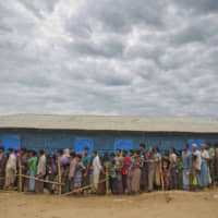Rohingya Muslims, who crossed over from Myanmar into Bangladesh, wait to receive aid at the Kutupalong refugee camp in Ukhiya, Bangladesh, in 2017. | AP