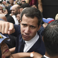 Juan Guaido, president of the National Assembly who swore himself in as the leader of Venezuela, gestures while leaving from a National Assembly session on rejoining the Inter-American Treaty of Reciprocal Assistance, known as the Rio Treaty, in the Las Mercedes neighborhood of Caracas on Tuesday. The agreement, known in Spanish as TIAR, allows for countries of the Hemisphere to request support in case of aggression. | BLOOMBERG