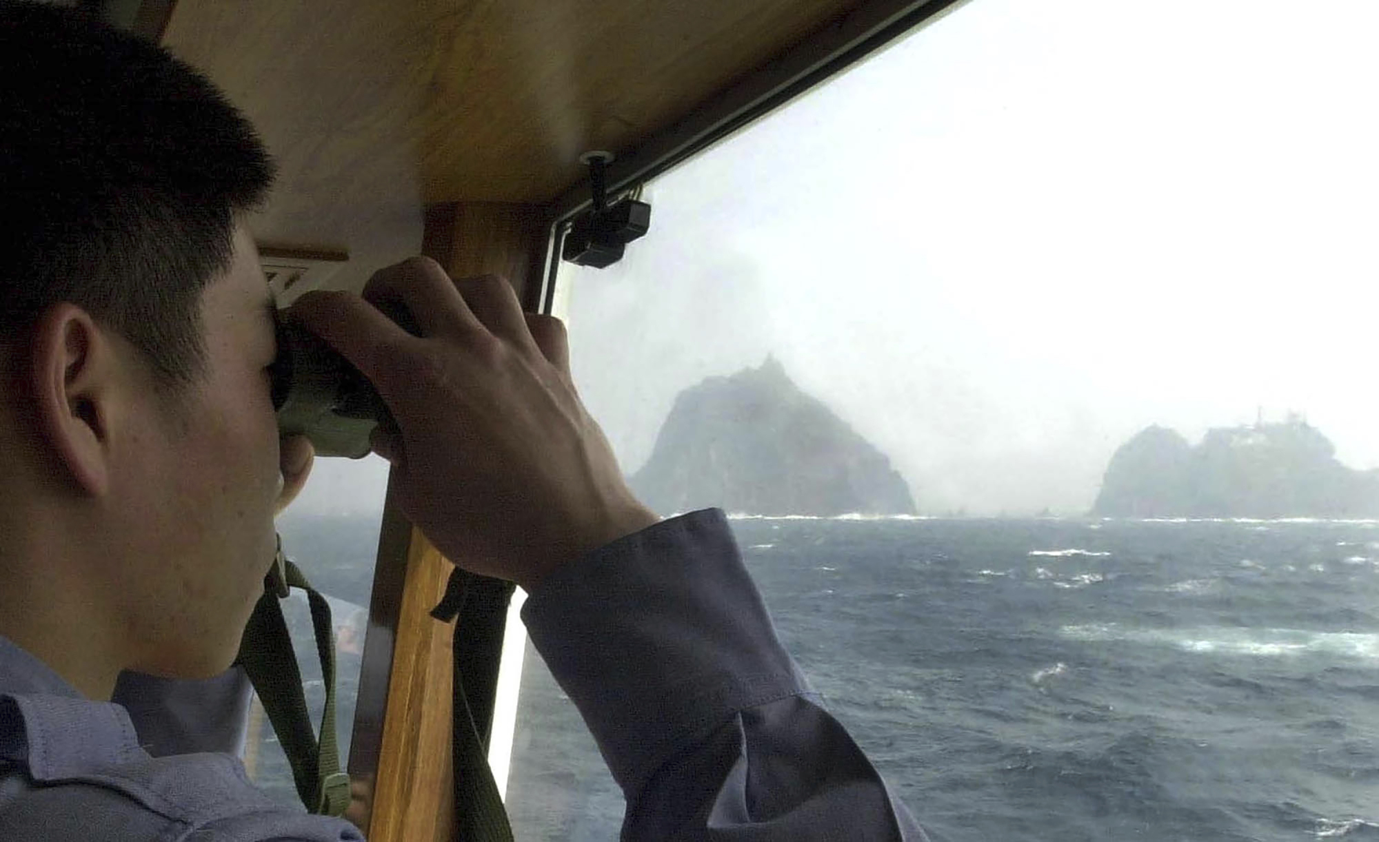 A member of the South Korean Coast Guard looks at the Takeshima islets, known in the South as Dokdo, aboard a patrol ship in the Sea of Japan in April 2005. South Korean jets fired warning shots after a Russian military plane violated South Korea's airspace on Tuesday, Seoul officials said, in the first such incident between the countries. | AP