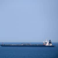 A British Royal Navy ship patrols near the supertanker Grace 1, which is suspected of carrying crude oil to Syria in violation of EU sanctions, after it was detained off the coast of Gibraltar on Thursday. | AFP-JIJI
