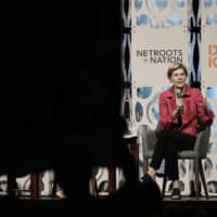 Democratic presidential candidate Elizabeth Warren addresses shouting people who stood up with a large banner while Warren was speaking during a forum sponsored by Netroots, Saturday at the Pennsylvania Convention Center in Philadelphia. | ELIZABETH ROBERTSON / THE PHILADELPHIA INQUIRER / VIA AP