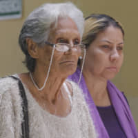 Carmen Arevalo de Acosta and Carmen Acosta, mother and sister of Navy Capt. Rafael Acosta, walk out of the morgue in Caracas Wednesday. | AP