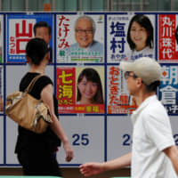 People walk past election campaign posters outside a voting station in Tokyo during Sunday\'s Upper House election. | REUTERS