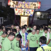 Fans of Kyoto Animation Co.\'s works observe a moment of silence Sunday night in Kuki, Saitama Prefecture, before they carried a portable shrine on their shoulders decorated with characters from \"Lucky Star,\" a production of Kyoto Animation studios. | KYODO