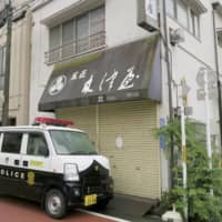 A police car is parked Sunday in front of a confectionery shop in Tokyo’s Arakawa Ward where the body of an 18-year-old female college student was found in a refrigerator. | KYODO