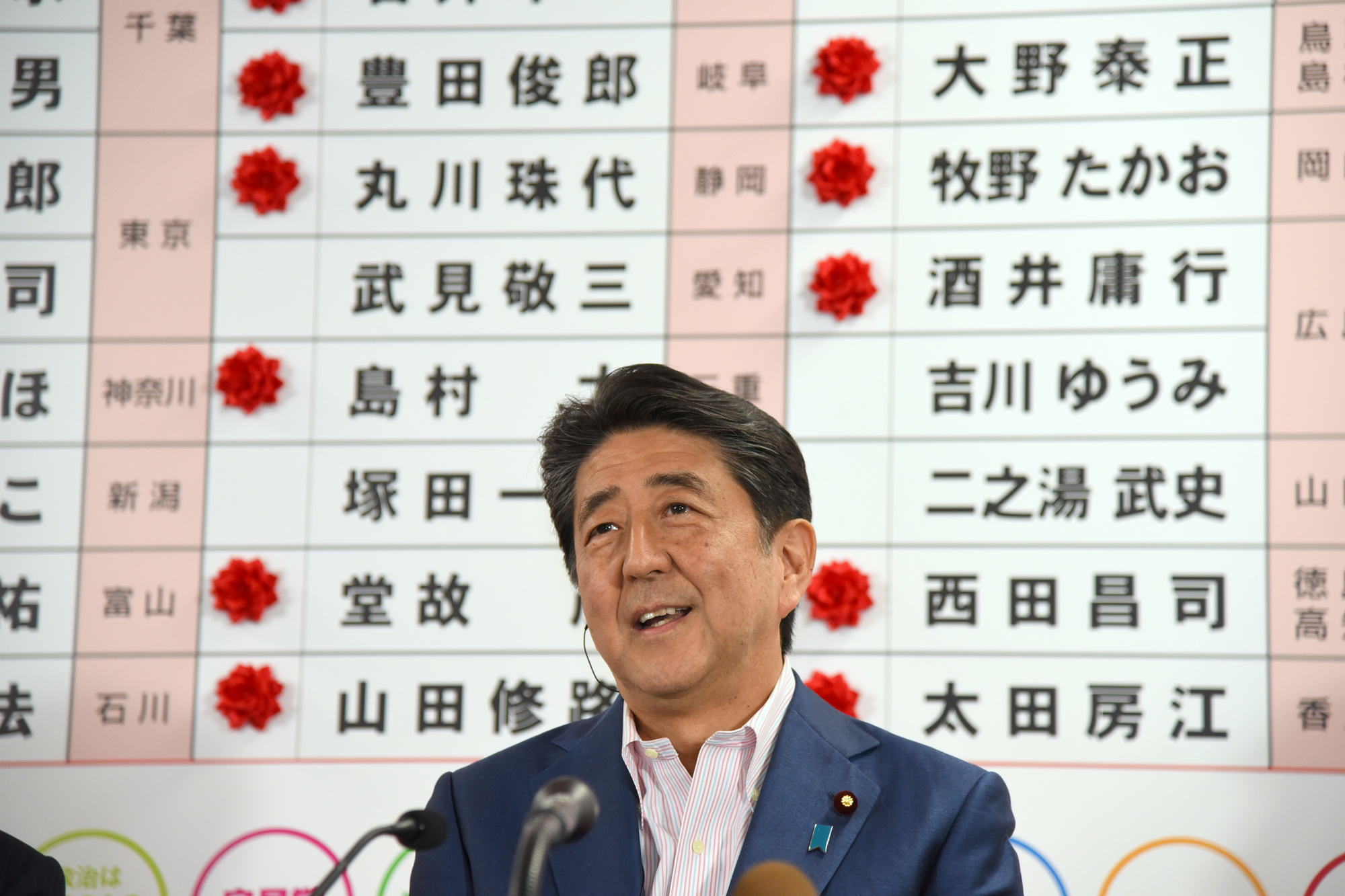 Prime Minister Shinzo Abe, president of the ruling Liberal Democratic Party, speaks to the media on Sunday night at the party's headquarters in Tokyo. On the board behind Abe, the names of LDP candidates who won seats are marked with paper flowers. | SATOKO KAWASAKI