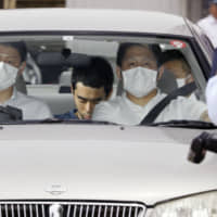 Yujiro Iimori, 33, (center rear) who allegedly stabbed a police officer and snatched his gun, leaves Suita police station in Osaka Prefecture on June 18. | KYODO