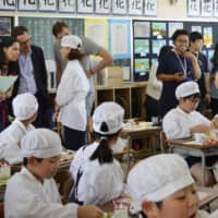 Journalists from Group of 20 countries and regions observe children eating prepared lunches at an elementary school in Osaka in May, as part of a program of events leading up to the summit in June. | KYODO