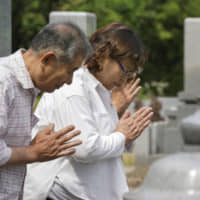 Reiko Kurozumi, who lost her father in floods triggered by torrential rain in Mabi, Okayama Prefecture, observes a moment of silence Saturday for victims of the deadly flooding and mudslides that hit western Japan last July, on the first anniversary of the disaster. | KYODO