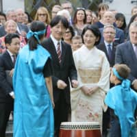 Crown Prince Akishino and his wife, Crown Princess Kiko, chat with children after a drum performance during a reception in Warsaw on Monday held to mark a century of Japanese ties with Poland. | POOL / VIA KYODO