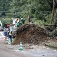 A mudslide partially blocks a road in Soo, Kagoshima Prefecture, on Thursday after heavy rain hit Kyushu the previous day. | KYODO