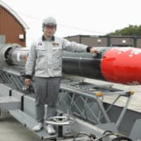 Takahiro Inagawa, president of Interstellar Technologies Inc., shows off the Momo-4 rocket Thursday, which the firm plans to launch from Taiki, Hokkaido. | KYODO