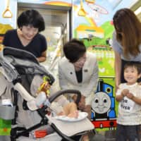Tokyo Gov. Yuriko Koike (center) speaks to a child in a Tokyo subway car decorated with characters from the popular children\'s animation \"Thomas &amp; Friends\" during its test runs Tuesday. | KYODO