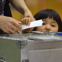 A girl watches as her mother casts her ballot in the Upper House election at a polling station in Tokyo on Sunday. | AFP-JIJI