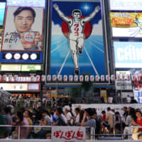 People walk around the Dotonbori downtown area of Osaka last month. Japan saw a record 16.63 million overseas visitors in the first six months of this year, according to government data released Wednesday. | BLOOMBERG