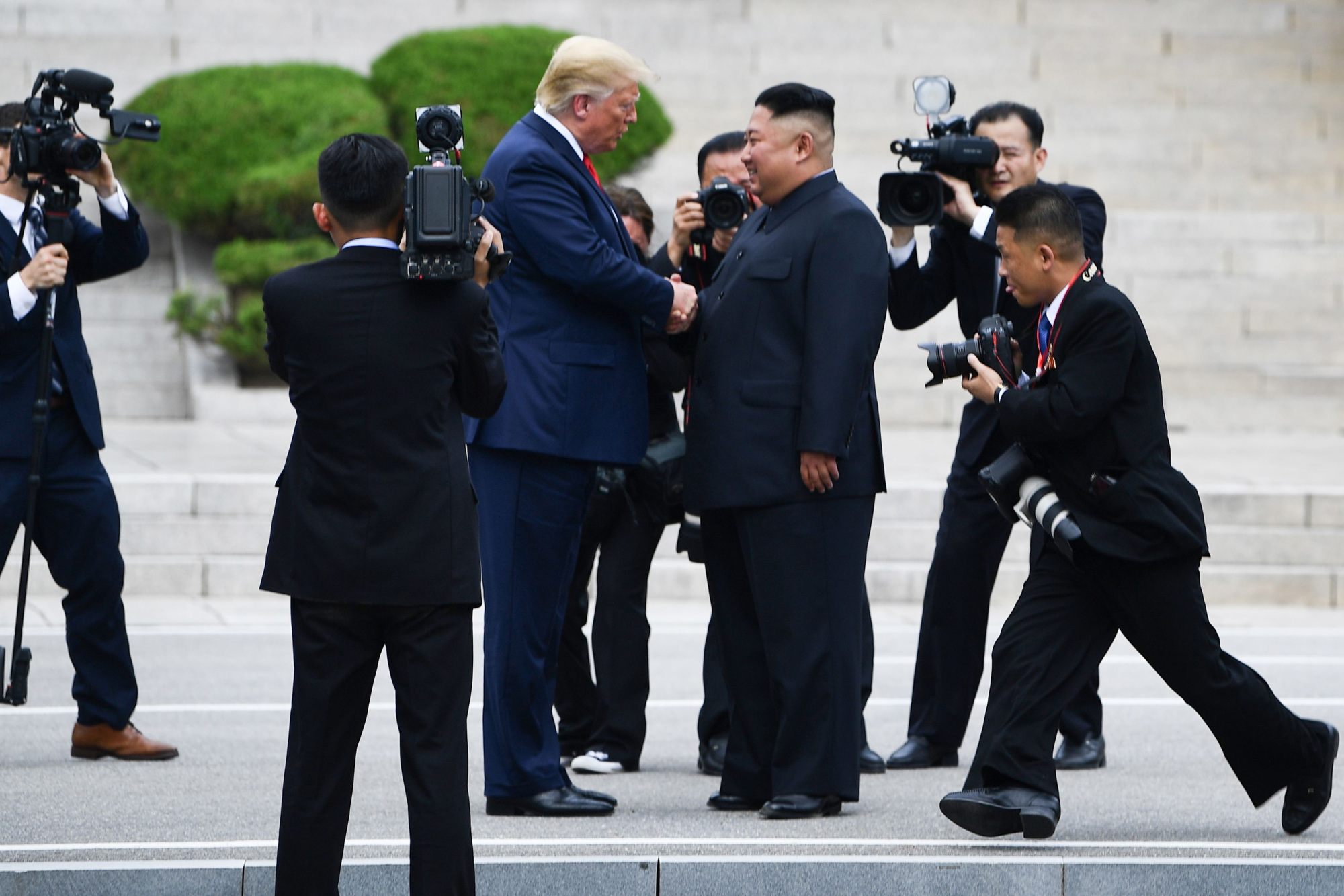 U.S. President Donald Trump and North Korean leader Kim Jong Un shake hands at the DMZ on Sunday. | AFP-JIJI