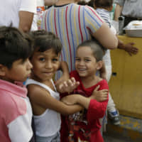 Children wait their turn to be served food on July 13 at a migrant campsite in Matamoros, Mexico, near the  border with the United States. | AP