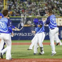 The BayStars\' Toshiro Miyazaki has water thrown on him by teammates after his sayonara single against the Swallows on Wednesday in Yokohama. | KYODO