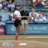 Naomi Osaka prepares to throw the ceremonial first pitch as Dodgers pitcher Kenta Maeda squats behind home plate before a game between the Dodgers and Angels on Wednesday at Dodger Stadium. | KYODO