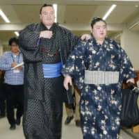 Yokozuna Hakuho, helped by his tsukebito, leaves Ryogoku Kokugikan during the New Year Basho in 2018. | KYODO