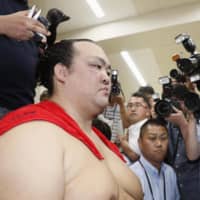 Yokozuna Kisenosato is surround by media in his changing room after his victory on the first day of the Autumn Basho last year. | KYODO